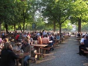 A crowd of people sitting at tables in the sun.